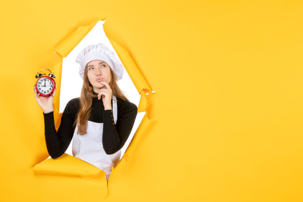 vue de face femme cuisinier tenant des horloges sur le temps jaune travail photo emotion cuisine soleil cuisine couleur